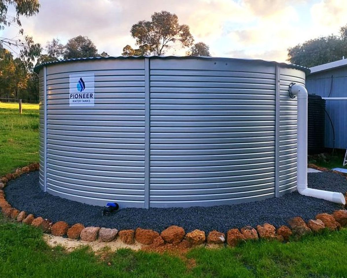 Pioneer water tank installed on a gravel pad with a rock border